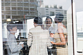 Smiling business people talking at sunny office window