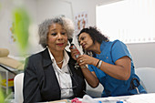 Doctor examining ear of senior patient with otoscope