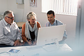 Doctor meeting with senior couple at computer