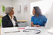 Doctor talking with senior patient at computer
