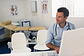 Confident doctor working at computer in doctors office