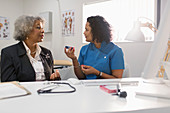 Doctor teaching senior patient how to use glucometer