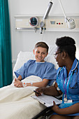 Female nurse talking with boy patient in hospital room