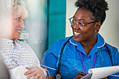 Friendly nurse talking with senior patient in hospital