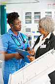 Female doctor and nurse with clipboard talking in hospital