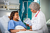 Female doctor talking with girl patient in hospital room