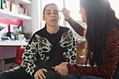Teenage girl applying eyeshadow makeup to friends eyes
