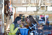 Young women looking into shopping bag in cafe window