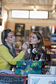 Young women applying lip gloss in cafe window
