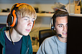 Teenage boys with headsets playing video game at computer