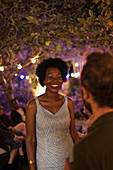 Happy young woman talking with man at garden party
