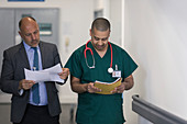 Male administrator and surgeon reading paperwork