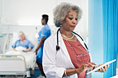 Female senior doctor using digital tablet in hospital room
