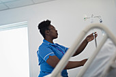 Female nurse adjusting IV drip in hospital room