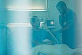 Male nurse examining patient in hospital bed