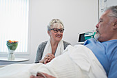 Senior woman visiting, comforting husband resting