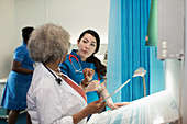 Doctor and nurse with tablet talking in hospital room