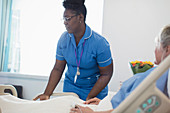 Female nurse helping patient in hospital bed