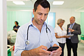 Male doctor using smart phone in hospital ward