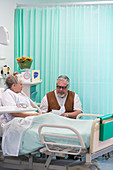 Senior man with greeting card visiting wife resting