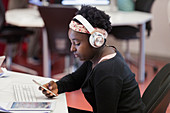 Female student with headphones using smart phone