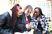 Young women friends using smart phone
