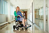 Woman wearing medical boot in wheelchair in corridor