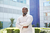 Portrait man with arms crossed outside sunny building