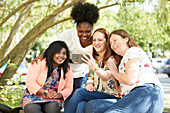 Happy female friends using smart phone