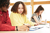 Focused college students studying together in classroom
