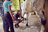 Woman teaching girls how to clean horse hoof