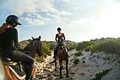 Young women horseback riding on sunny beach