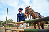 Girl in equestrian helmet with horse at obstacle