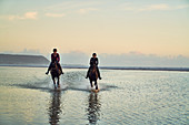 Young women horseback riding in ocean surf