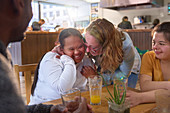 Happy mentor and women with Down Syndrome laughing in cafe