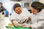 Women with Down Syndrome cutting potatoes in kitchen