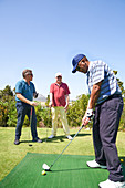 Male golfer practicing swing at golf driving range