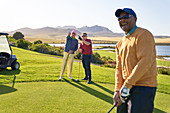 Male golfers talking on sunny golf course