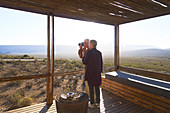 Senior couple with camera on sunny safari cabin balcony