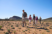 Guide leading group in sunny grassland South Africa