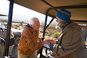Senior couple getting into safari off-road vehicle