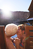 Happy romantic senior couple kissing on sunny balcony