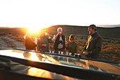 Safari tour group drinking champagne at sunset