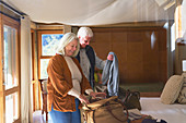 Senior couple unpacking luggage in hotel room
