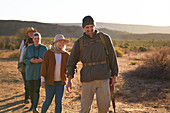 Smiling safari tour guide leading group in sunny grassland