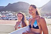 Young female surfers with surfboards on sunny beach