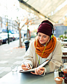 Woman with headphones writing in journal