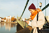 Woman using smart phone on autumn bridge