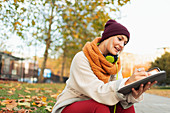 Woman writing in journal in autumn park