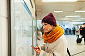 Woman with smart phone checking subway map